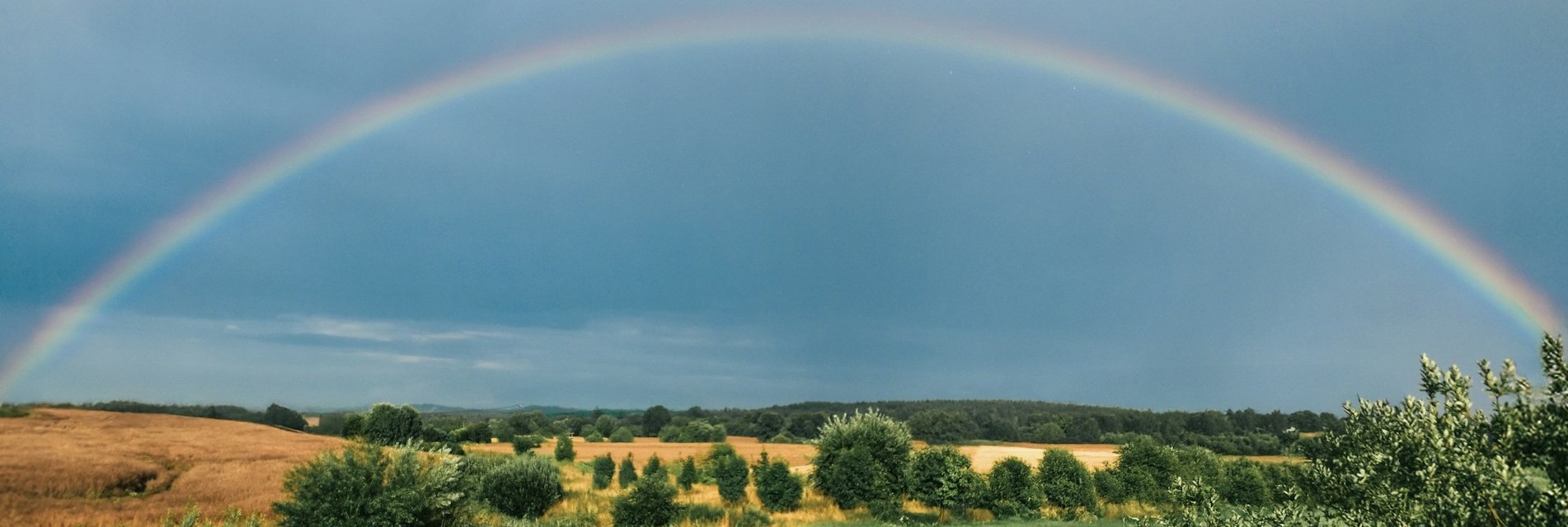 A full rainbow arc over a green field
